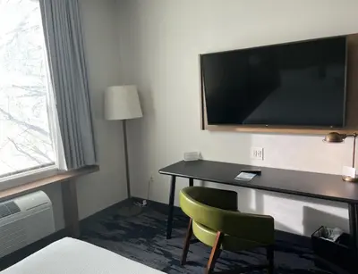 a room with a desk with a television and a chair at Fairfield Inn & Suites by Marriott Queensbury Glens Falls/Lake George in Queensbury
