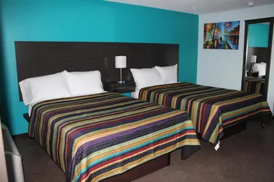 two beds in a hotel room with blue walls at Castle Inn East Greenbush Castleton-on-hudson in East Greenbush