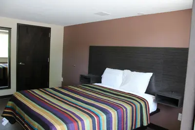 a hotel room with a bed with a colorful striped blanket at Castle Inn East Greenbush Castleton-on-hudson in East Greenbush