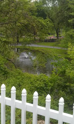 a white fence in front of a pond at Community Court Motel in Saratoga Springs