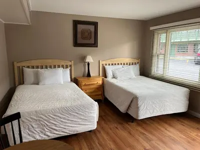 a bedroom with two beds and a window at Community Court Motel in Saratoga Springs