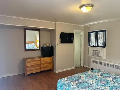 a bedroom with a bed and a dresser and a television at Community Court Motel in Saratoga Springs
