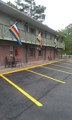 a parking lot with flags in front of a building at Community Court Motel in Saratoga Springs