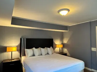 a bedroom with a large white bed with two lamps at Community Court Motel in Saratoga Springs