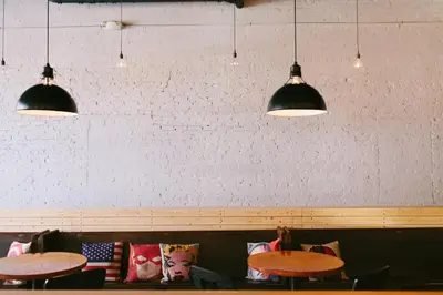 a restaurant with two tables and three pendant lights at The Local NY Hostel in Queens