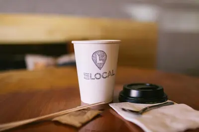 a coffee cup sitting on top of a table at The Local NY Hostel in Queens