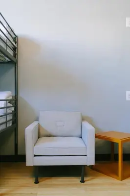 a white chair in a room with a table at The Local NY Hostel in Queens
