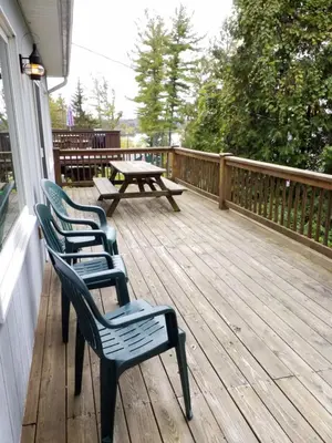 three chairs and a picnic table on a deck at Bayside Inn & Marina in Cooperstown