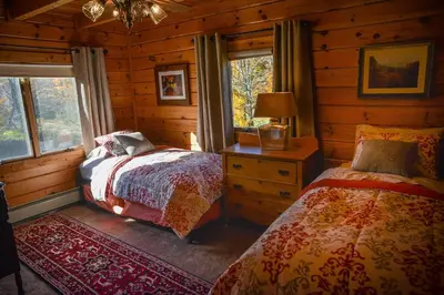 a bedroom with two beds in a log cabin at Colgate Lake Lodge in East Jewett