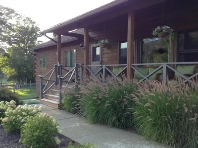 a log cabin with a porch and a fence at Colgate Lake Lodge in East Jewett