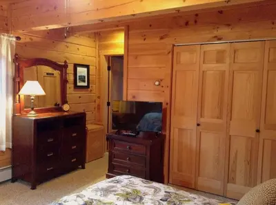 a bedroom with a bed and a dresser and a mirror at Colgate Lake Lodge in East Jewett