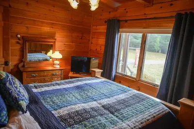 a bedroom with a bed and a television in a cabin at Colgate Lake Lodge in East Jewett