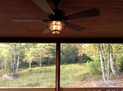 a ceiling fan and a window with a view of a forest at Colgate Lake Lodge in East Jewett