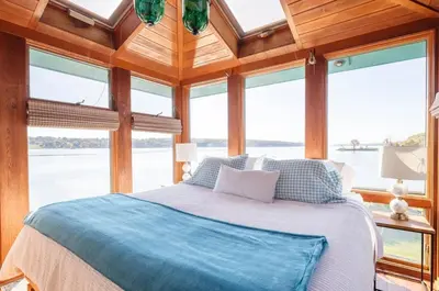 a bedroom with a bed in a room with windows at Hudson Riverfront Home in Catskill
