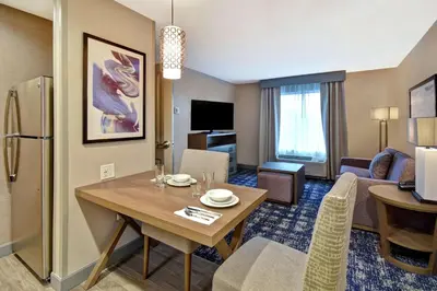 a living room with a table and a room with a couch at Homewood Suites By Hilton Orange New Haven in Orange