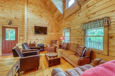 a living room with furniture and a tv in a log cabin at Log Cabin Escape in Jacksonville