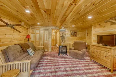 a living room with a couch and a tv in a cabin at Log Cabin Escape in Jacksonville