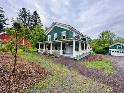 a green house with a porch and a yard at Mill Pond Inn in Jefferson