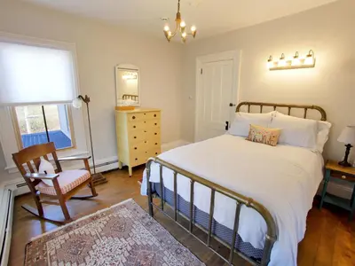 a bedroom with a bed and a chair and a window at Mill Pond Inn in Jefferson