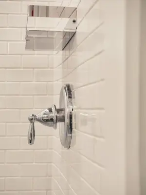 a shower head in a white tiled bathroom at Mill Pond Inn in Jefferson