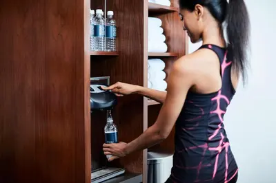 a woman is putting a bottle of water in a drink dispenser at Hotel Boutique at Grand Central in New York