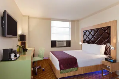 a hotel room with a bed and a desk and a television at Night Hotel Broadway in New York