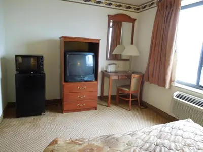 a bedroom with a television and a desk with a bed at Red Carpet Inn Brooklyn in Brooklyn