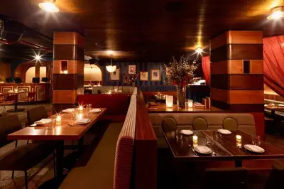 a restaurant with wooden tables and chairs and lights at The Renwick in New York
