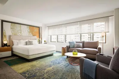 a bedroom with a bed and a couch and a table at The Gardens Sonesta ES Suites New York in New York