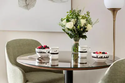 a table with a vase of flowers and two chairs at The Gardens Sonesta ES Suites New York in New York