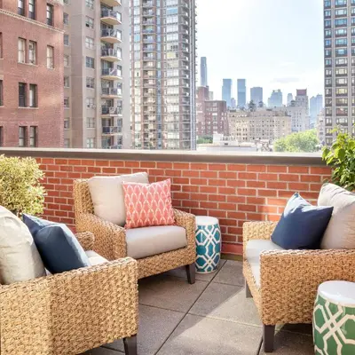 a patio with chairs and pillows on a balcony at The Gardens Sonesta ES Suites New York in New York