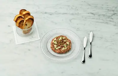 a table with a plate of pizza and a basket of bread at The Benjamin Royal Sonesta New York in New York