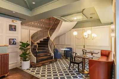 a lobby with a staircase and a table and chairs at The Benjamin Royal Sonesta New York in New York