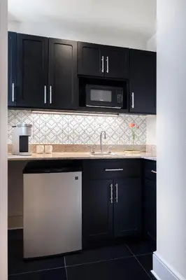 a kitchen with black cabinets and a sink at The Benjamin Royal Sonesta New York in New York