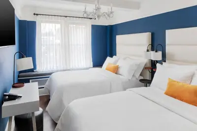 two beds in a room with blue walls at voco The Franklin New York by IHG in New York