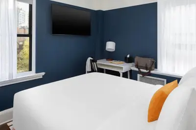 a bedroom with a blue wall with a bed and a desk at voco The Franklin New York by IHG in New York