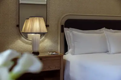 a bedroom with a bed and a lamp and a mirror at The Surrey, A Corinthia Hotel in New York