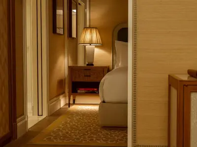 a bedroom with a chair and a lamp on a table at The Surrey, A Corinthia Hotel in New York