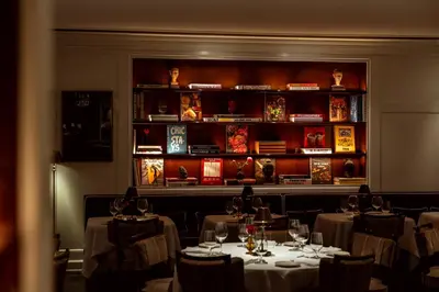 a restaurant with tables and chairs and a book shelf at The Surrey, A Corinthia Hotel in New York