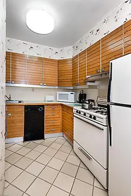 a kitchen with a white refrigerator and wooden cabinets at Murray Hill East Suites - Extended Stay in New York
