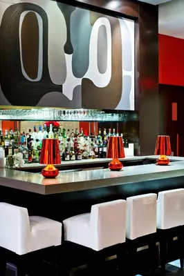a bar with white chairs and red lamps at Ameritania at Times Square in New York