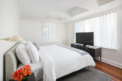 a white bedroom with a bed and a television at AKA Sutton Place in New York