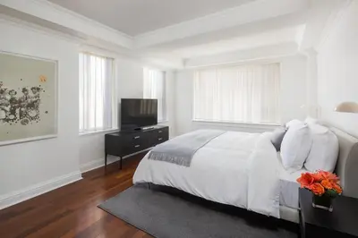 a white bedroom with a bed and a flat screen tv at AKA Sutton Place in New York