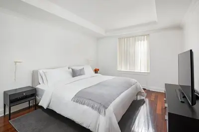 a white bedroom with a bed and a flat screen tv at AKA Sutton Place in New York