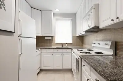 a white kitchen with white cabinets and a white refrigerator at The Bayard in New York