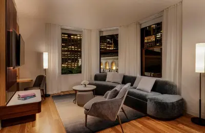a living room with a couch and chairs and windows at Bryant Park Hotel in New York