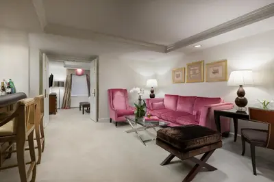 a living room with a pink couch and chairs at The Michelangelo New York in New York