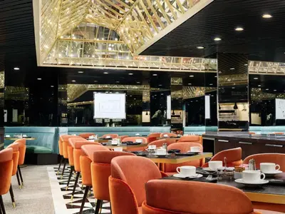 a restaurant with orange chairs and tables and a screen at Millennium Hilton New York One UN Plaza in New York
