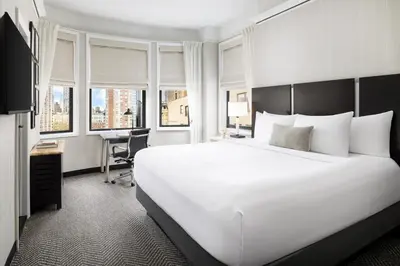 a bedroom with a large white bed and a desk at The Gregorian New York City in New York