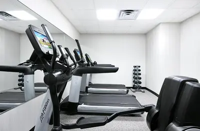 a gym with a row of tread machines in a room at The Gregorian New York City in New York